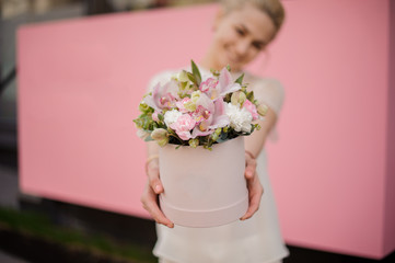 Smiling girl holding bouquet in pink hat box