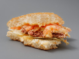 bitten big burger with cutlet cheese and tomato on a gray background