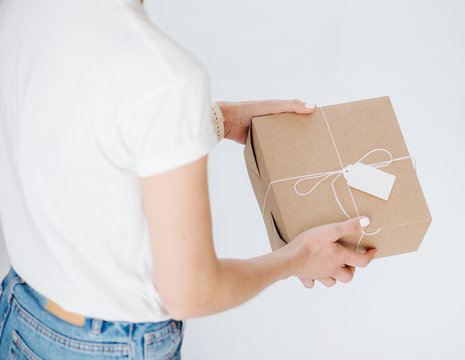Woman in casual clothes holding postal cardboard box, checking wrappings over white