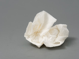 crumpled used white paper napkin on a gray background