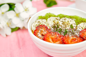 Healthy breakfast bowl smoothie with strawberry, banana, kiwi  and chia seeds on pink background. Healthy vegan food concept..