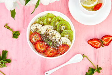 Healthy breakfast bowl smoothie with strawberry, banana, kiwi  and chia seeds on pink background. Healthy vegan food concept..
