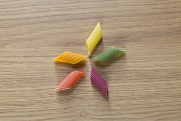 Obraz na płótnie Canvas Pasta mezze penne rigate di semola colorate su tavolo di legno