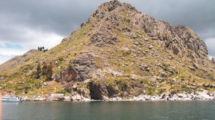 Fototapeta na wymiar Small island with cloudy sky on lake titicaca in Bolivia