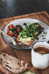 Healthy vegan summer lunch. Avocado toast on sourdough bread with chives, coriander and cherry-tomatoes with cup of coffee on board. Vegetarian, dieting, alkiline diet, clean eating concept