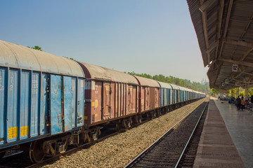 Indian freight train at the train station near the platform under a canopy with people