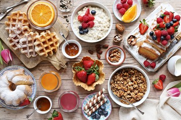 Fototapeta na wymiar Happy breakfast with granola, oatmeal porridge, smoothies, fresh waffles, sweets, fruits and berries.