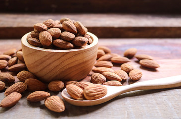 Almond nuts in wooden bowl on rustic background.