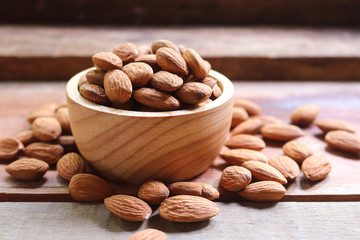 Almond nuts in wooden bowl on rustic background.
