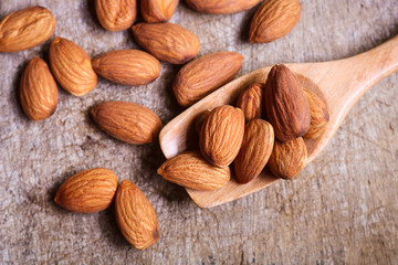 Almond nuts in wooden spoon on rustic background.