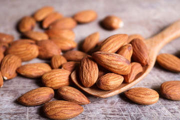 Almond nuts in wooden spoon on rustic background.