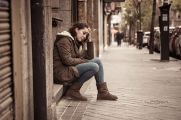 Depressed woman sitting on urban city street overwhelmed and hop