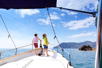 Naklejka premium Two adorable school kid boys, best friends enjoying sailing boat trip. Family vacations on sea on sunny day. Children smiling. Brothers, schoolchilden, siblings, best friends having fun on yacht.