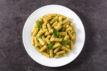 Penne pasta with pesto sauce on black background. Top view. 