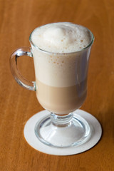 A cup of coffee standing on a wooden office table.