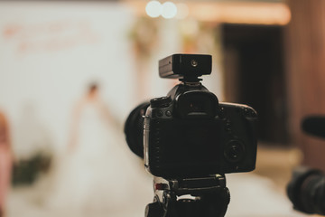 Close-up of professional DSLR digitak camera attached with tripod in wedding ceremony and with...