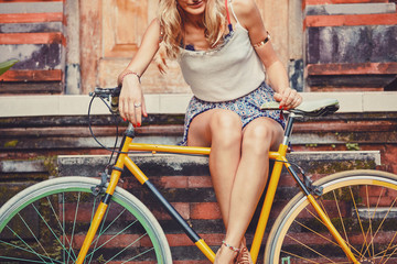 Fototapeta na wymiar Pretty woman sitting with old bicycle outdoors.