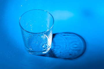 A glass with water drops  on a dark blue background close up