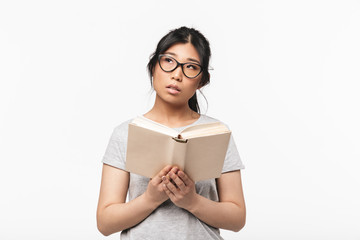Naklejka premium Beautiful young woman posing isolated over white wall background holding book reading.