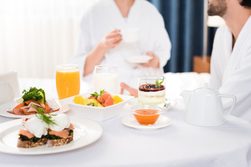 Obraz na płótnie Canvas selective focus of tasty breakfast on table near man and woman