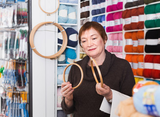 Senior woman choosing embroidery hoops in shop