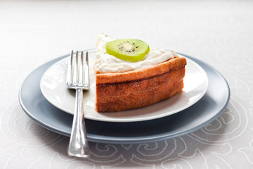 Homemade cottage cheese cake with kiwi fruit and cream on a plate