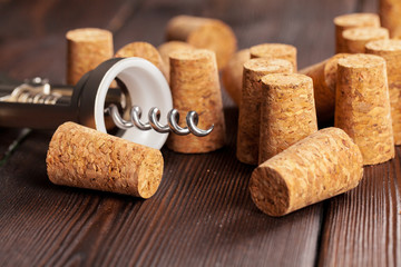 Wine corks with corkscrew on wooden table