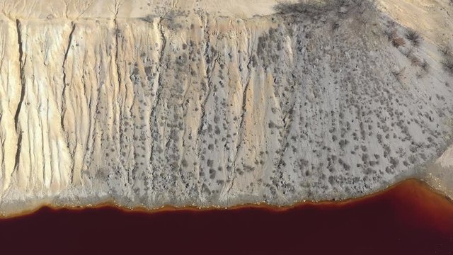 Pyrite from open-pit mine site and red acidic drainage 4K aerial video