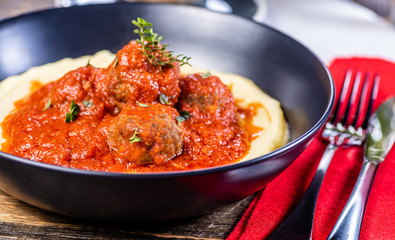 Traditional meatballs in tomato sauce on a bed of mashed potato in a blue bowl