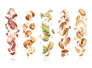 Set of various crushed nuts in the air on a white background