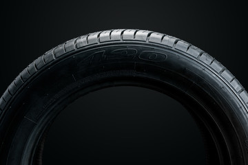 Brand new modern car tyre on a black background. Studio shot