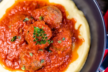 Traditional meatballs in tomato sauce on a bed of mashed potato in a blue bowl