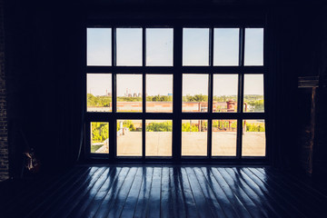 Asilhouette  huge panoramic window to the floor, contrasting lighting, a sunny day outside the window and twilight in the room. Industrial landscape.