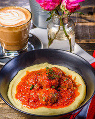 Traditional meatballs in tomato sauce on a bed of mashed potato in a blue bowl