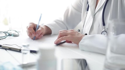 	 Woman doctor writes a medical report in the office of the clinic. - Powered by Adobe