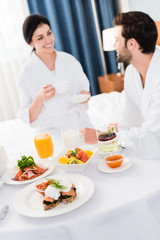 Obraz na płótnie Canvas selective focus of delicious breakfast near happy man and woman
