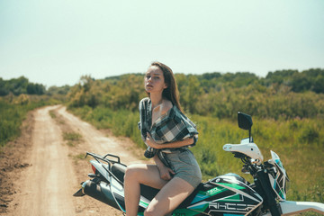 Fototapeta premium Young beautiful girl posing sitting on a motorcycle outdoors