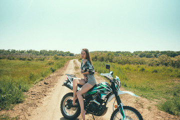 Obraz premium Young beautiful girl posing sitting on a motorcycle outdoors