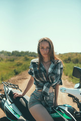 Young beautiful girl posing sitting on a motorcycle outdoors