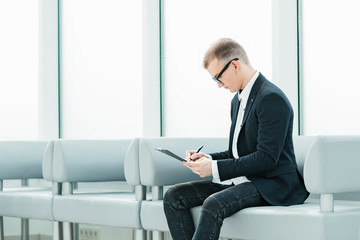 Fototapeta premium businessman reading a business document sitting in the office lobby