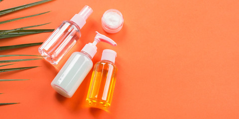 Generic beauty products on orange coral background. Summer travel kit or sun protection concept.