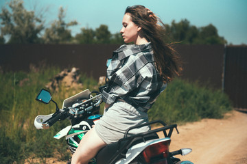 Fototapeta na wymiar Young beautiful girl posing sitting on a motorcycle outdoors