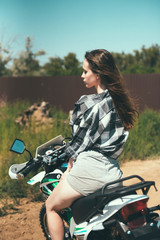 Fototapeta na wymiar Young beautiful girl posing sitting on a motorcycle outdoors