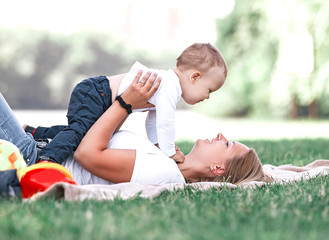 mom and her little son play together, lying on the lawn .