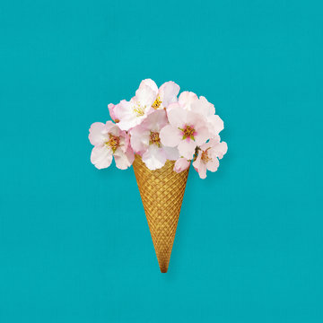 Ice cream cone with almond flowers, conceptual image on blue background. Creative design, spring summer decorative composition.