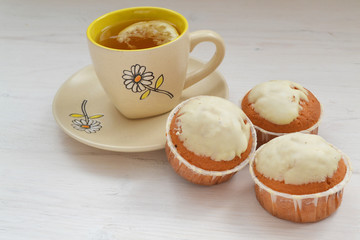 Lemon cupcakes with white icing and cup of tea