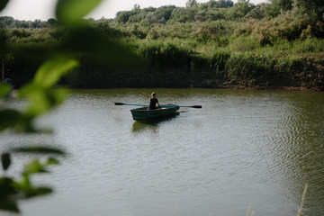 Young man floats on a wooden boat with oars © bo.kvk