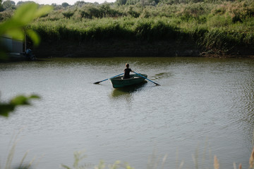 Young man floats on a wooden boat with oars