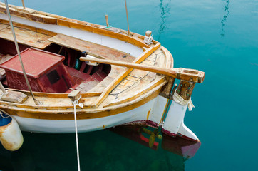 Back of an old wooden boat with a steering handle and propeller.