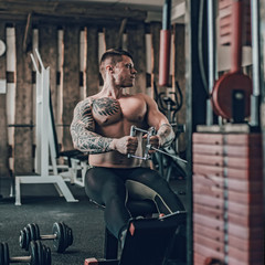 purposeful male bodybuilder performing exercises on the simulator